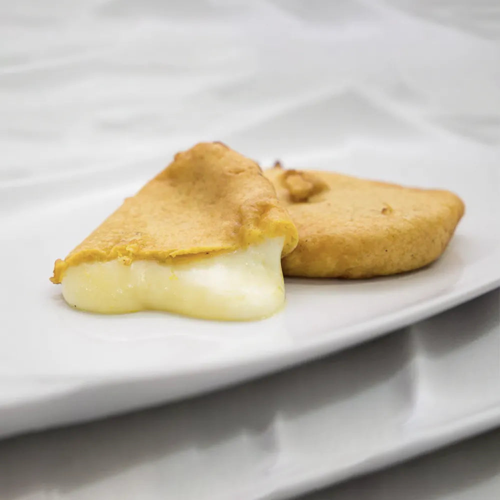 Foto di due fette di formaggio fritto una delle quali è tagliata e fuoriesce il formaggio fuso